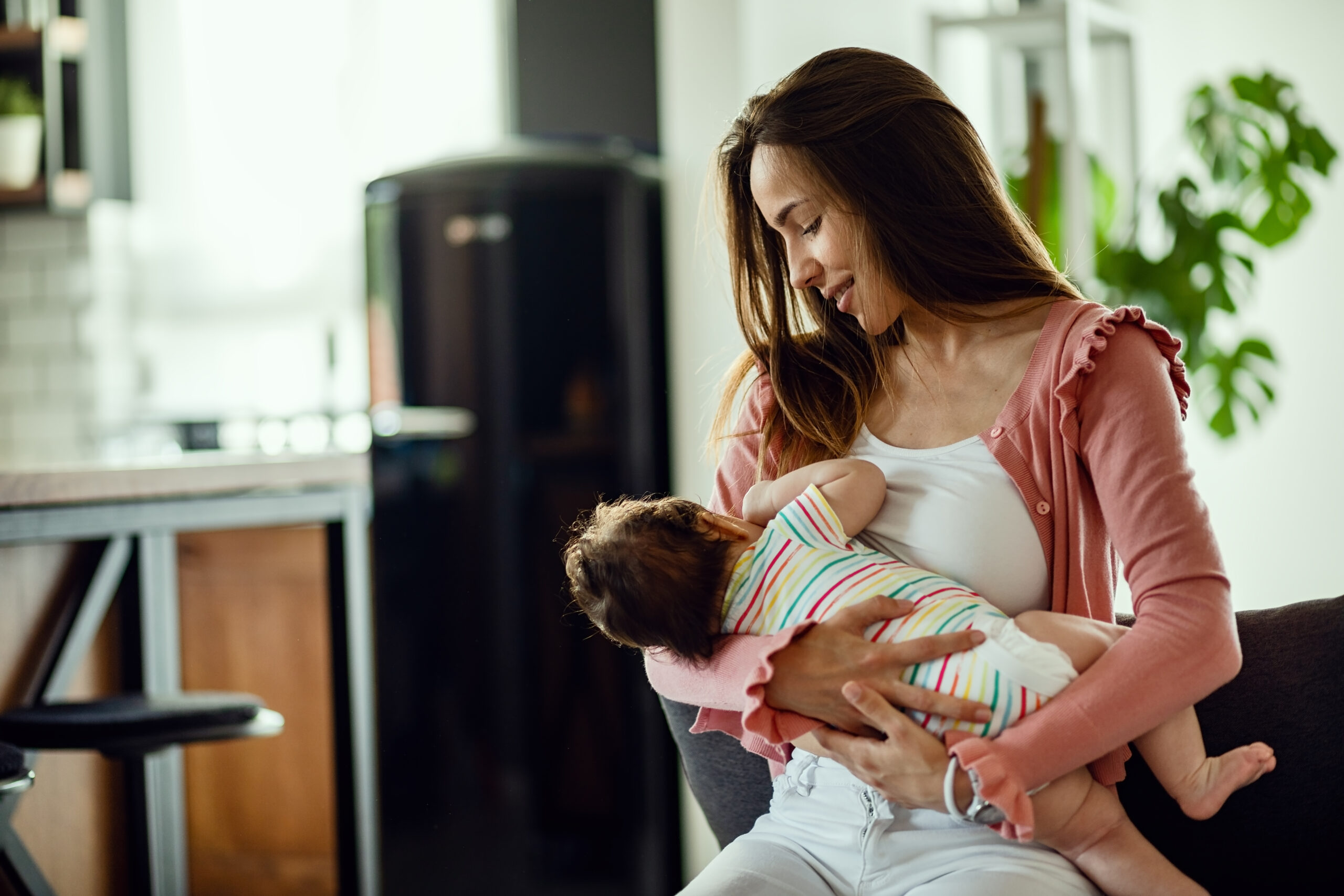 Young smiling mother breastfeeding