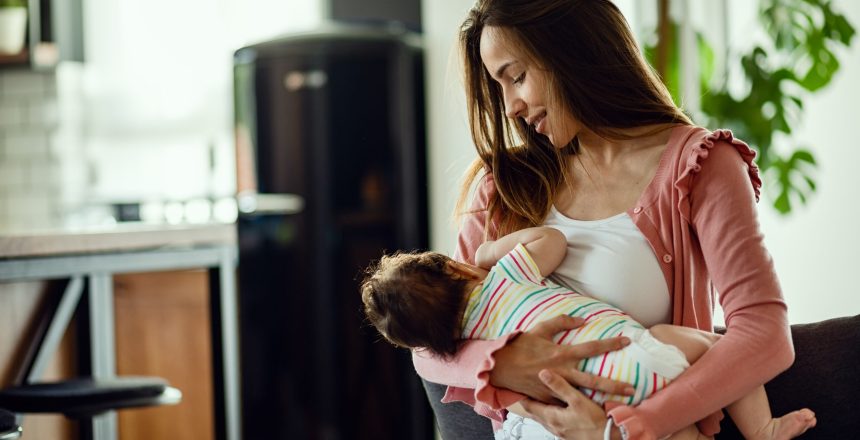 Young smiling mother breastfeeding